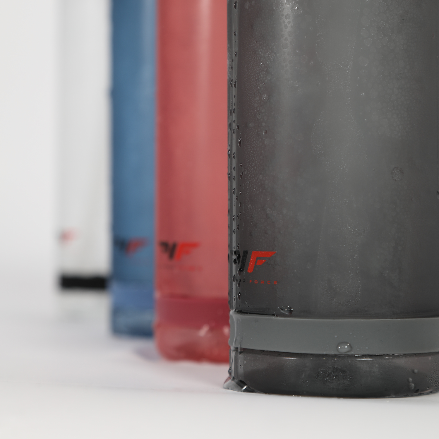 Close-up of four frosted bottles in white, blue, red, and black with condensation, featuring a red and black logo, on a white backdrop.