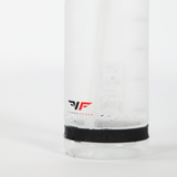 Close-up of a frosted glass bottle with a black band at the base. Water droplets cover the surface, and a red and black logo is visible. Clean, refreshing feel.