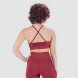 Back view of woman wearing red sports bra and leggings, bra has special design plus logo