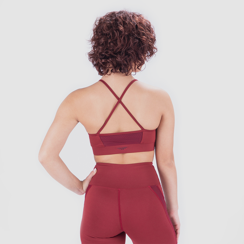 Back view of woman wearing red sports bra and leggings, bra has special design plus logo