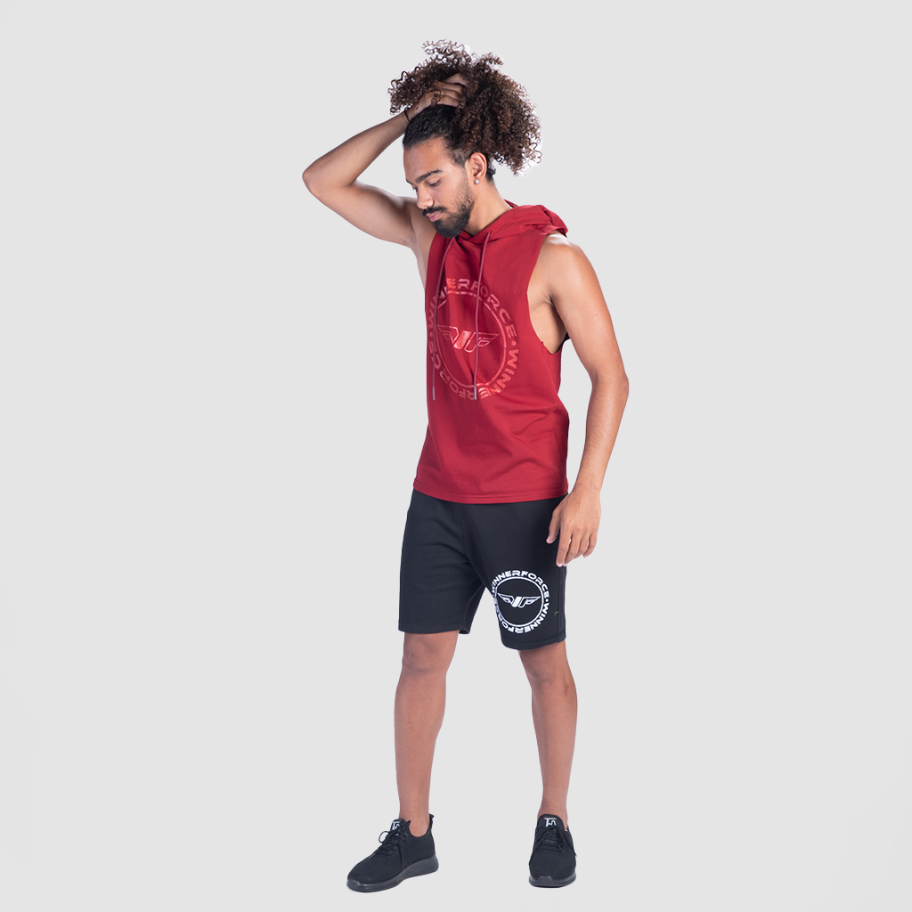 a fit man stand with pose and wearing half hoodie burgundies red with logo in half and short black ,plus shoes 