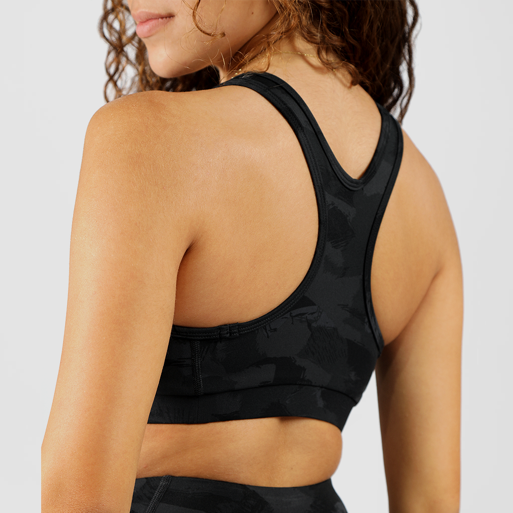 a back view for girl wearing  bras camo and legging with  background light Grey
