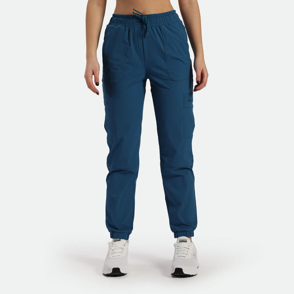 a fit woman wearing cargo pant blue with shoes white ,plus the background is light grey 
