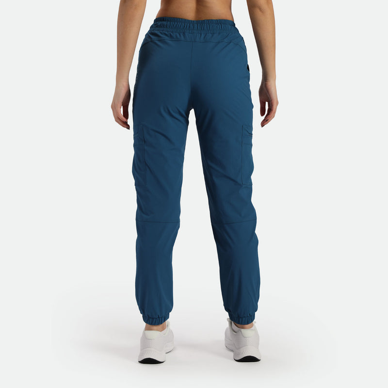 a back view for woman wearing cargo pant blue with shoes white ,plus the background is light grey  