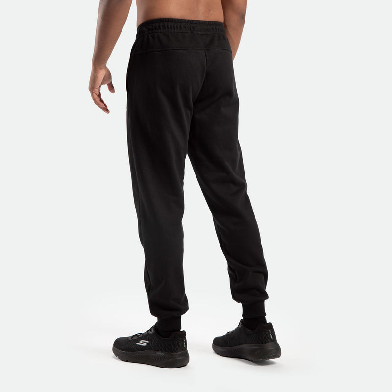 a back view for fit man stand at right and wearing jogger pants caviar black  , plus the shoes black 
