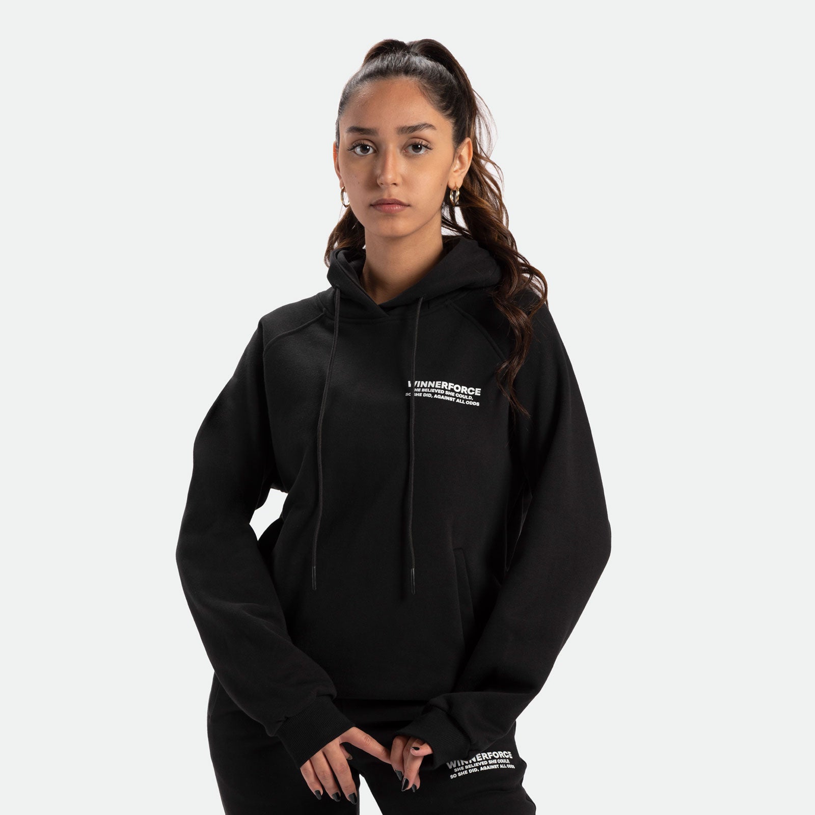 a fit woman wearing hoodie black with pants black ,plus the logo white 