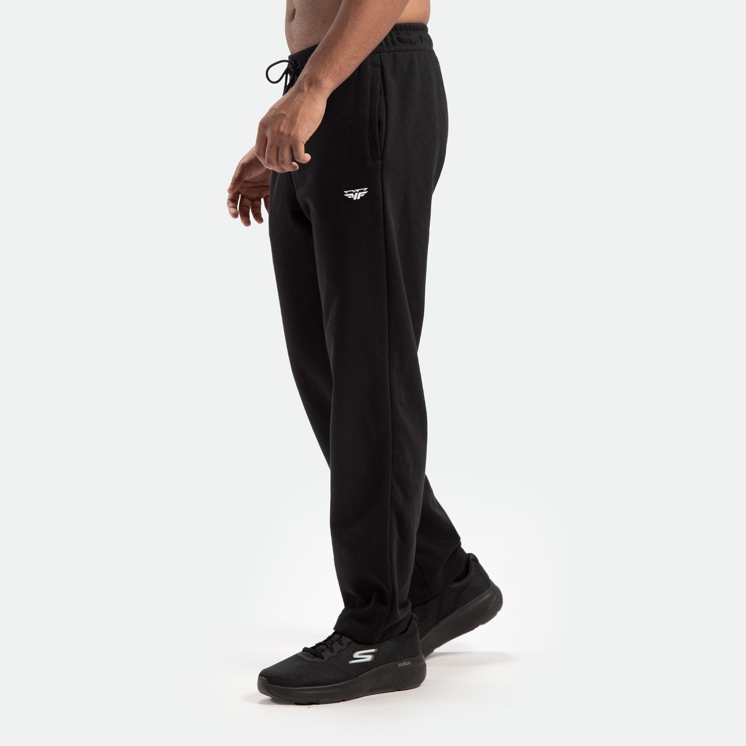 a fit man stand at right and wearing  pants black with shoes black 