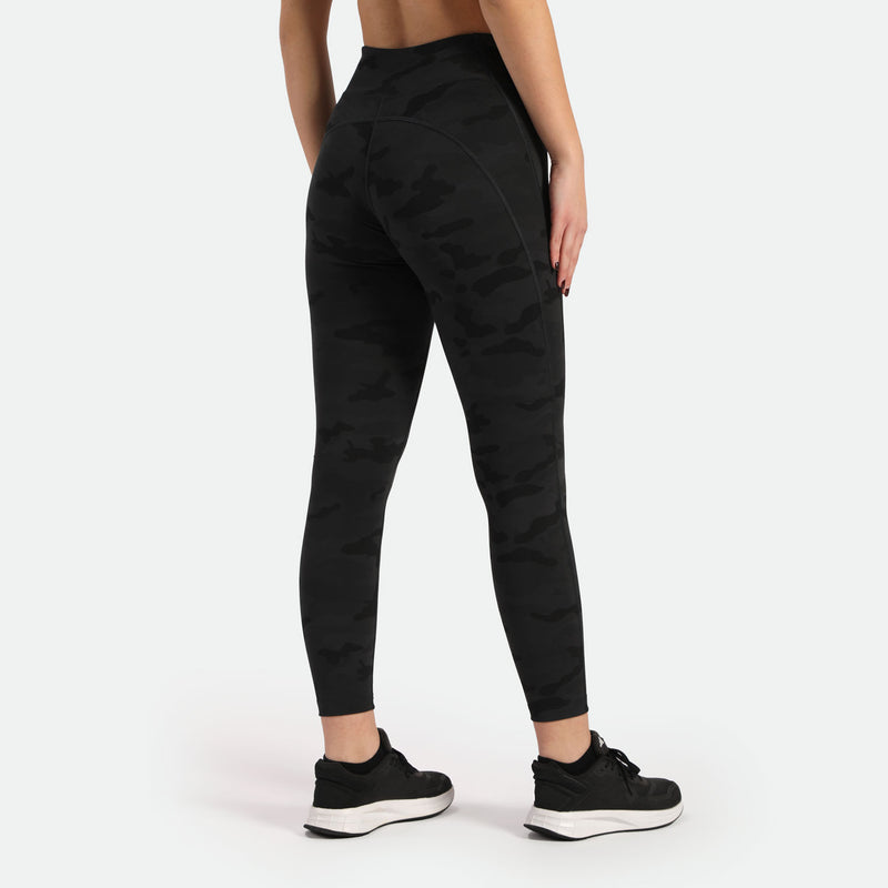 a back view for woman wearing camo legging with shoes black  ,plus the background is light black