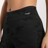 a woman wearing camo legging with  logo white ,plus background  light grey 