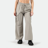 a fit woman wearing parachute pants  with black athletic shoes ,plus the background is light grey 