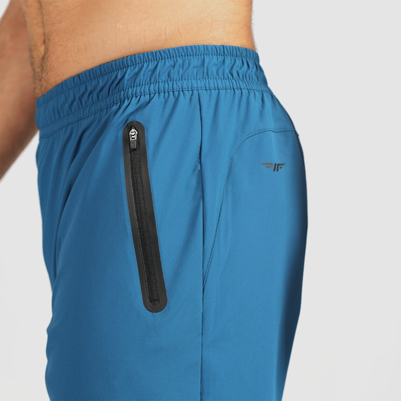 close up view for fit woman stand at right and wearing pants classic blue with logo and zipper 