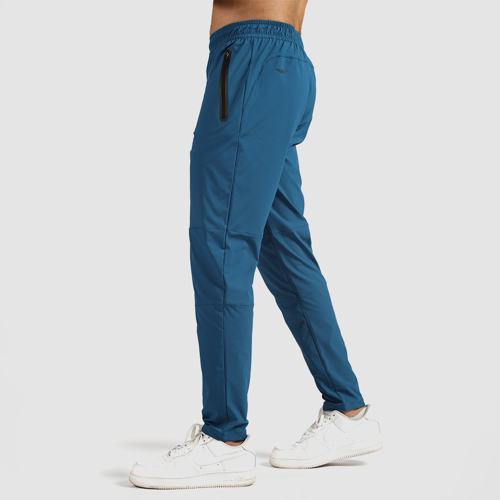 a fit man stand at right and wearing pants classic blue  with shoes white 