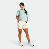 Woman wearing a light green shirt and white shorts on a white background