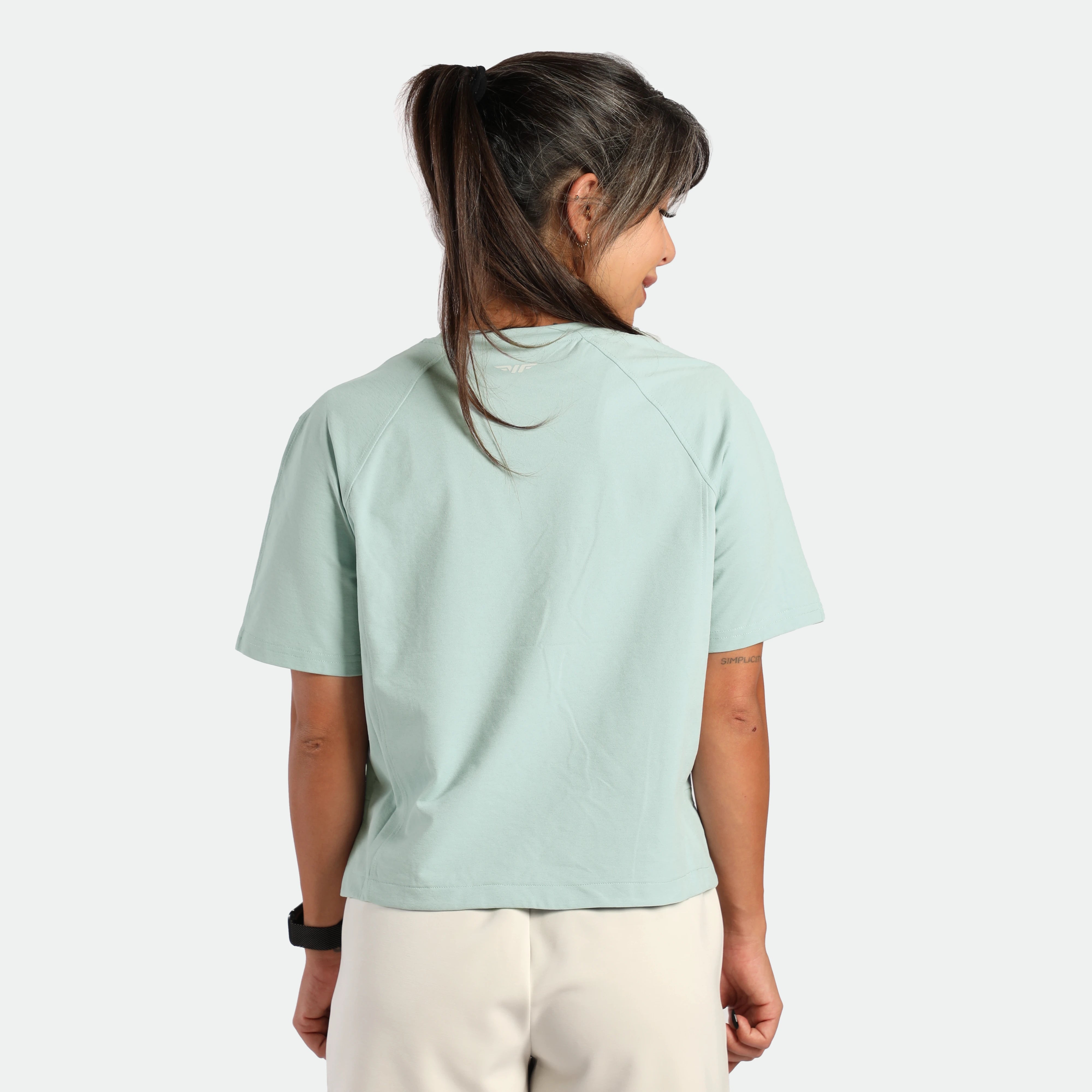 a back view for fit woman wearing t-shirt cloud blue with pants beige 