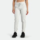 a fit woman wearing jogger pants cloud grey ,plus the shoes black 