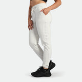 Person wearing white jogger pants and black sneakers on a white background
