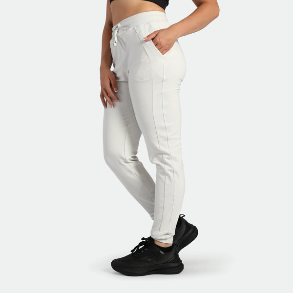 Person wearing white jogger pants and black sneakers on a white background