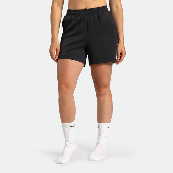 Person wearing black shorts and white socks on a plain background
