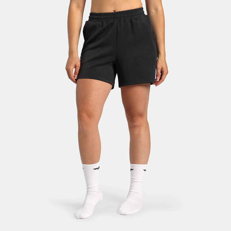 Person wearing black shorts and white socks on a plain background