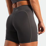 Person wearing black athletic shorts with a visible brand logo on a light gray background