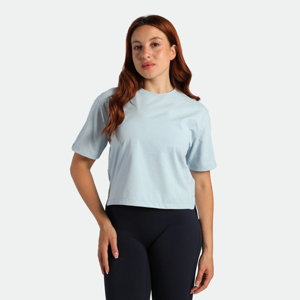 Woman wearing a light blue t-shirt and black leggings on a plain background