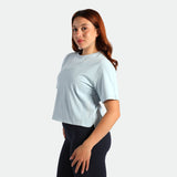 Woman wearing a light blue t-shirt and dark pants on a white background