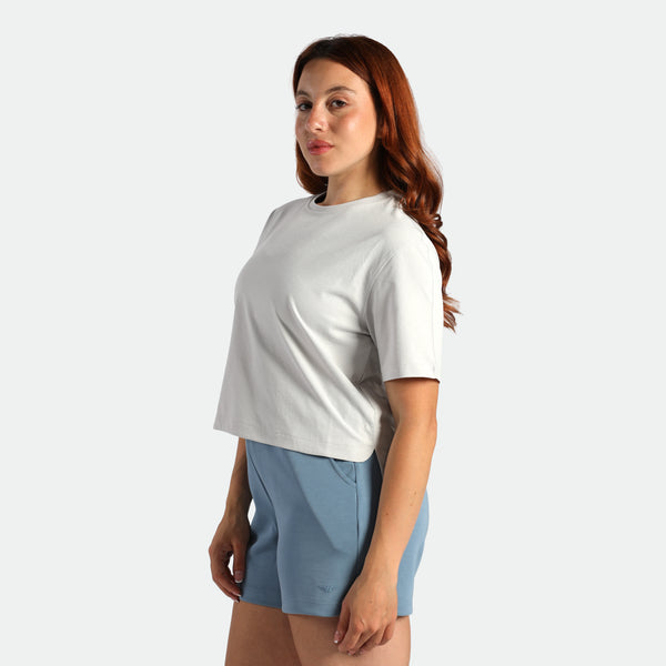 Woman wearing a white t-shirt and blue shorts on a light gray background
