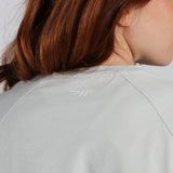 Person wearing a light gray jacket with a brand logo on the back