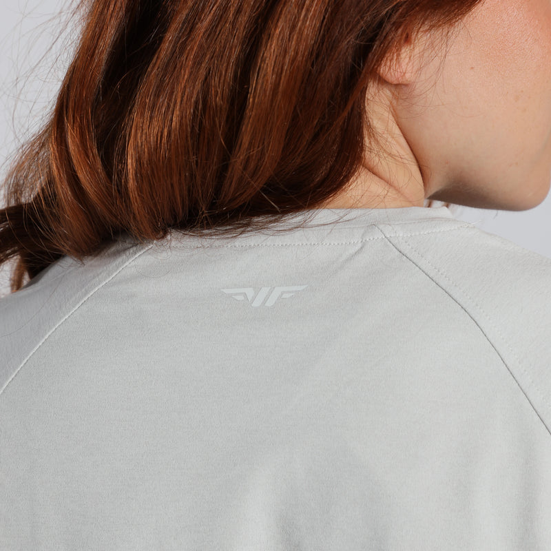 Person wearing a light gray jacket with a brand logo on the back