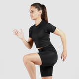 a fit woman stand with pose  sports like run, she wearing crop top and short matching color is black 