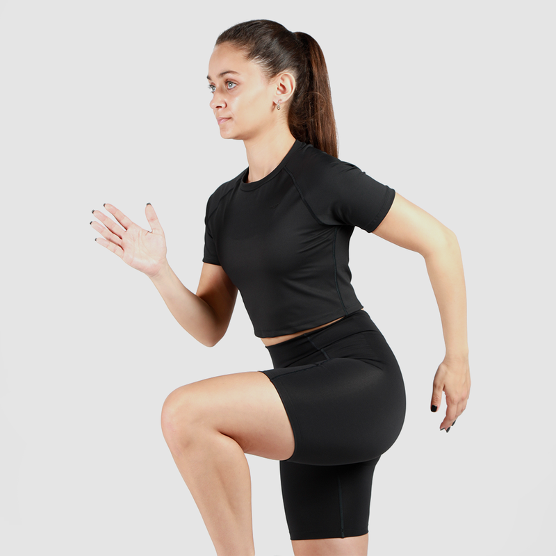 a fit woman stand with pose  sports like run, she wearing crop top and short matching color is black 