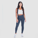 a fit woman wearing crop top  white with legging blue and sneakers 
