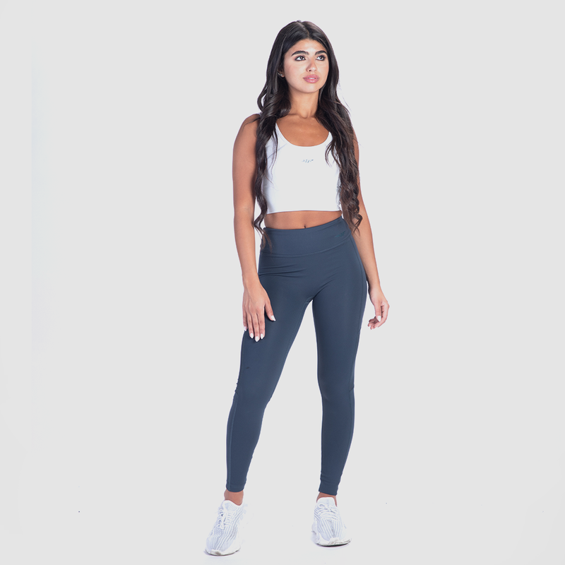 a fit woman wearing crop top  white with legging blue and sneakers 