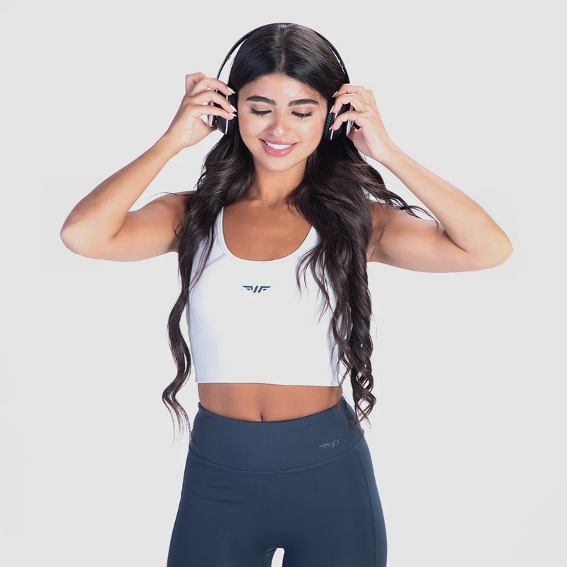 a fit woman wearing crop top white with  legging  blue and plus the logo 