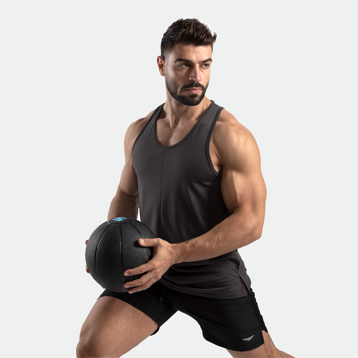 a fit man stand with exercise and hold bale, he wearing tank dark grey   with short black 
