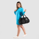a fit woman stand at right and wearing sweatshirt  blue  with sneakers and bag