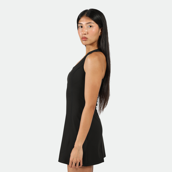 a fit woman stand at right and look at the camera  ,she wearing dress black 