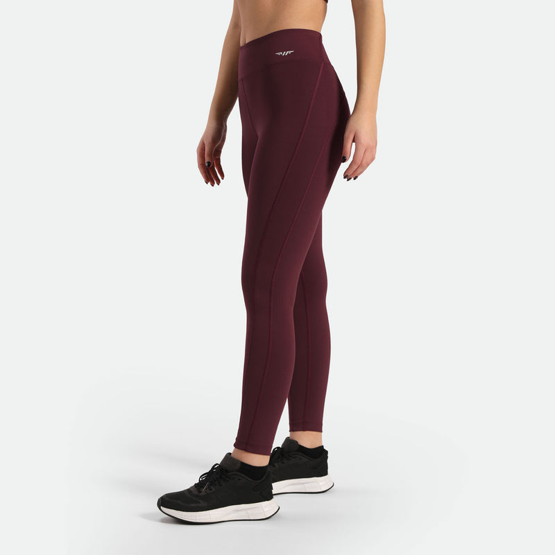   a  fit woman stand at right  and wearing legging red with logo white ,plus wearing shoes black ,the background is light grey 