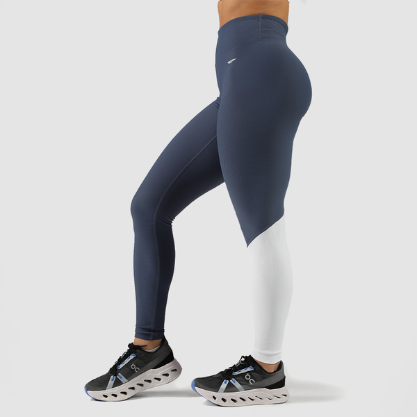  a fit woman stand at the right  and wearing legging mix tow color blue and white ,shoes is same color , plus background is light grey 