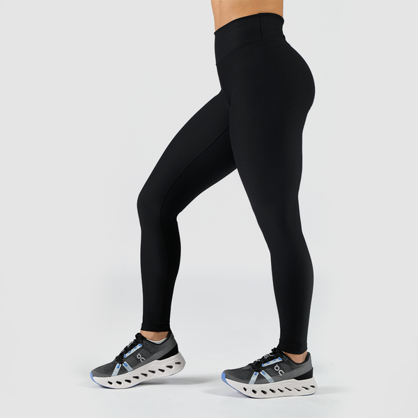 a woman stand at right and she wearing legging black and shoes ,the background is light grey 