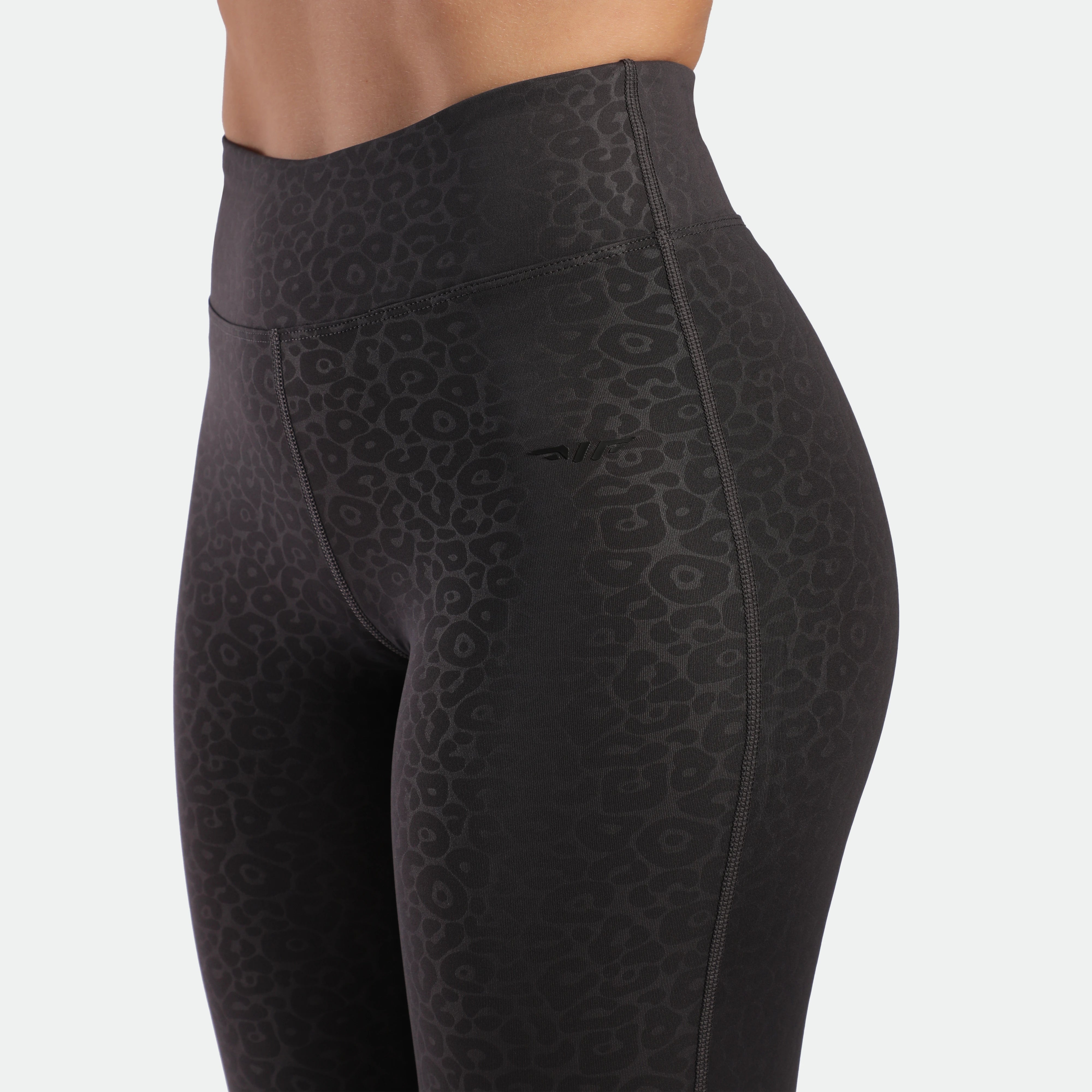 close up view for fit woman wearing flared legging graphite grey leopard ,with logo 