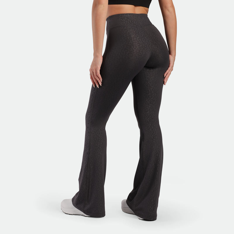 a back view for fit woman wearing flared legging graphite grey leopard with shoes 