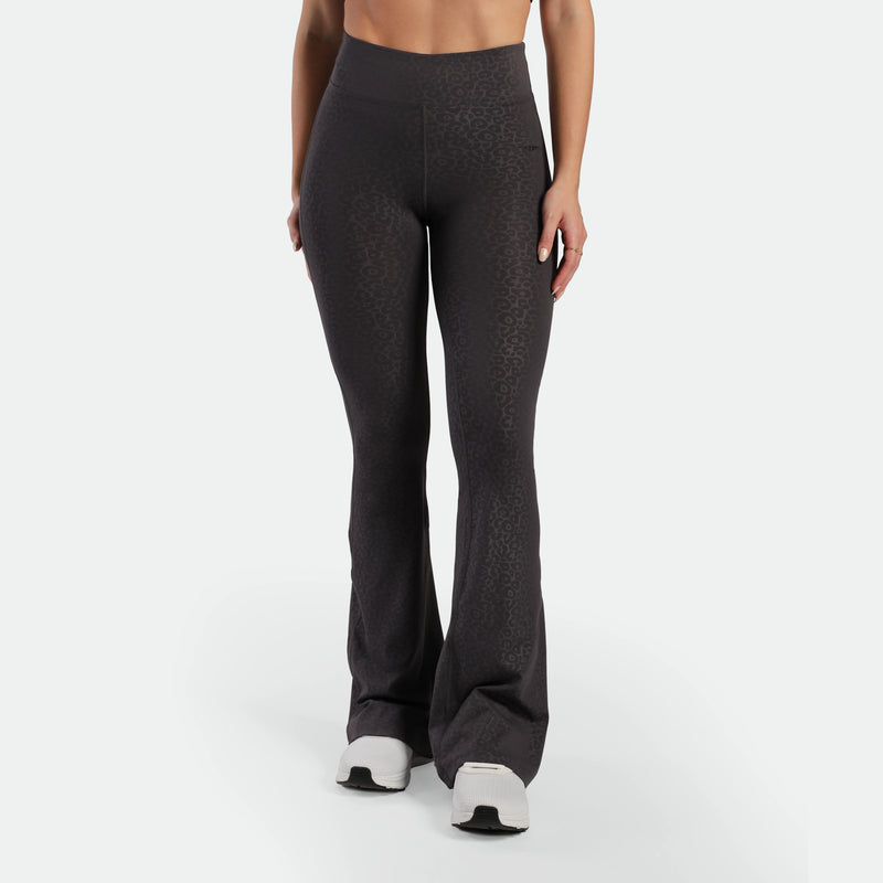 a fit woman wearing flared legging  
 graphite grey leopard with shoes 