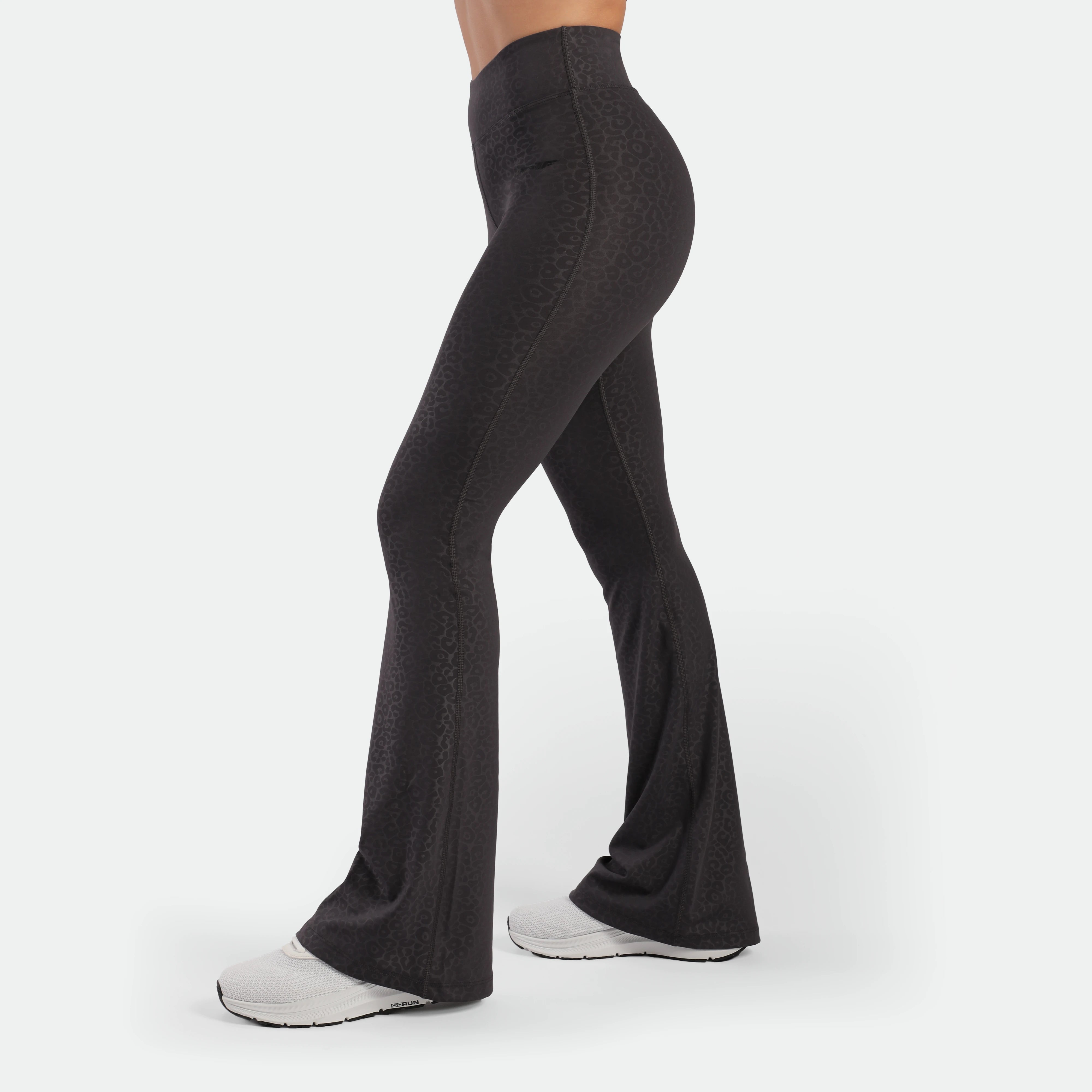 a fit woman stand at right and wearing flared legging graphite grey leopard  with shoes 
