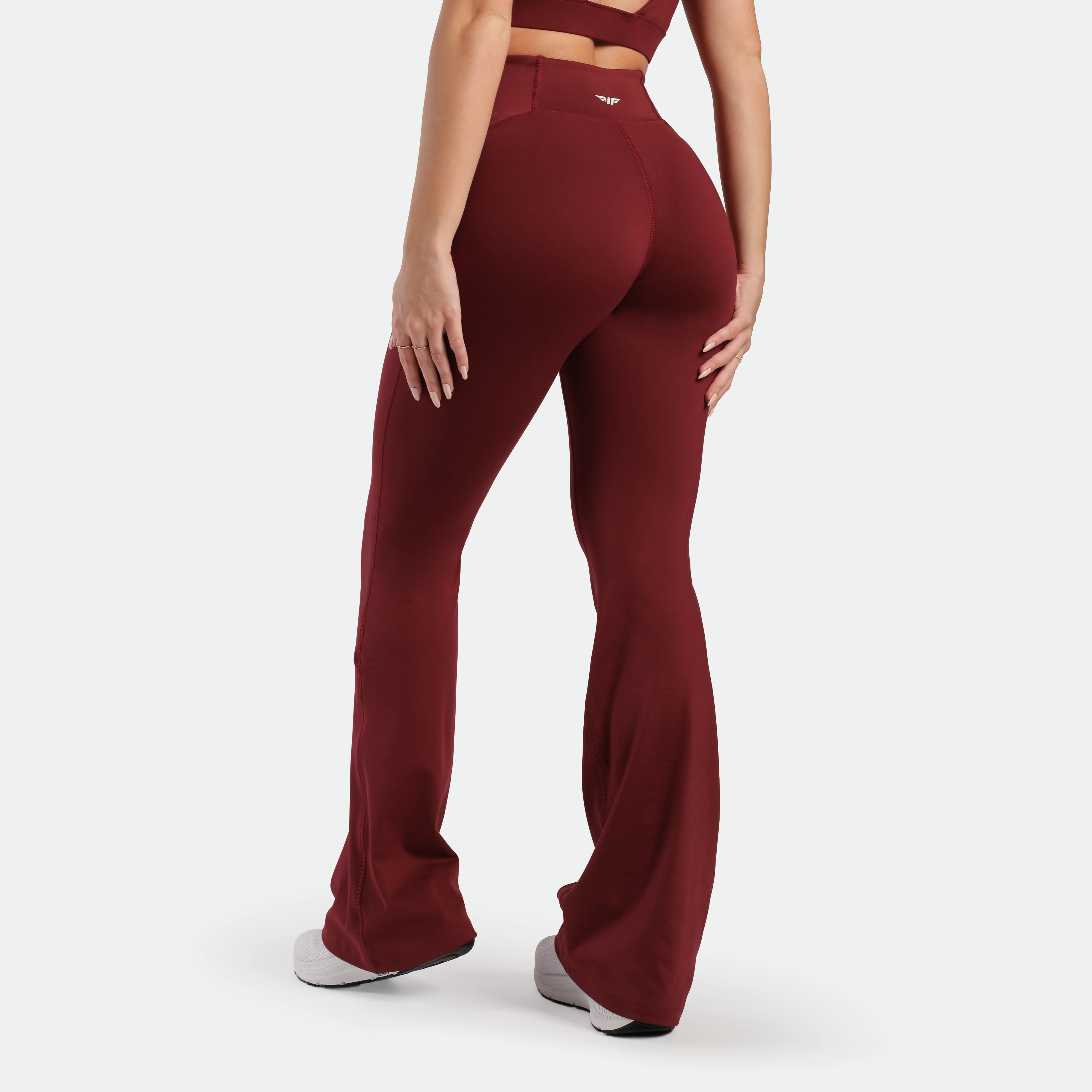 a back view for fit woman wearing flared legging pomegranate with shoes white 