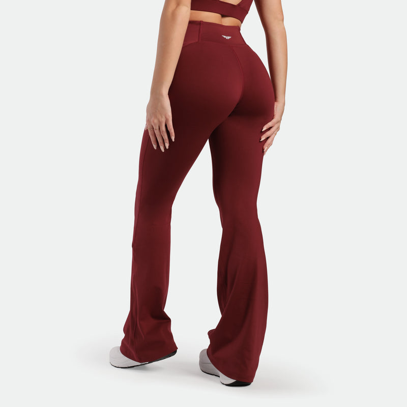 a back view for fit woman wearing flared legging pomegranate with shoes white 