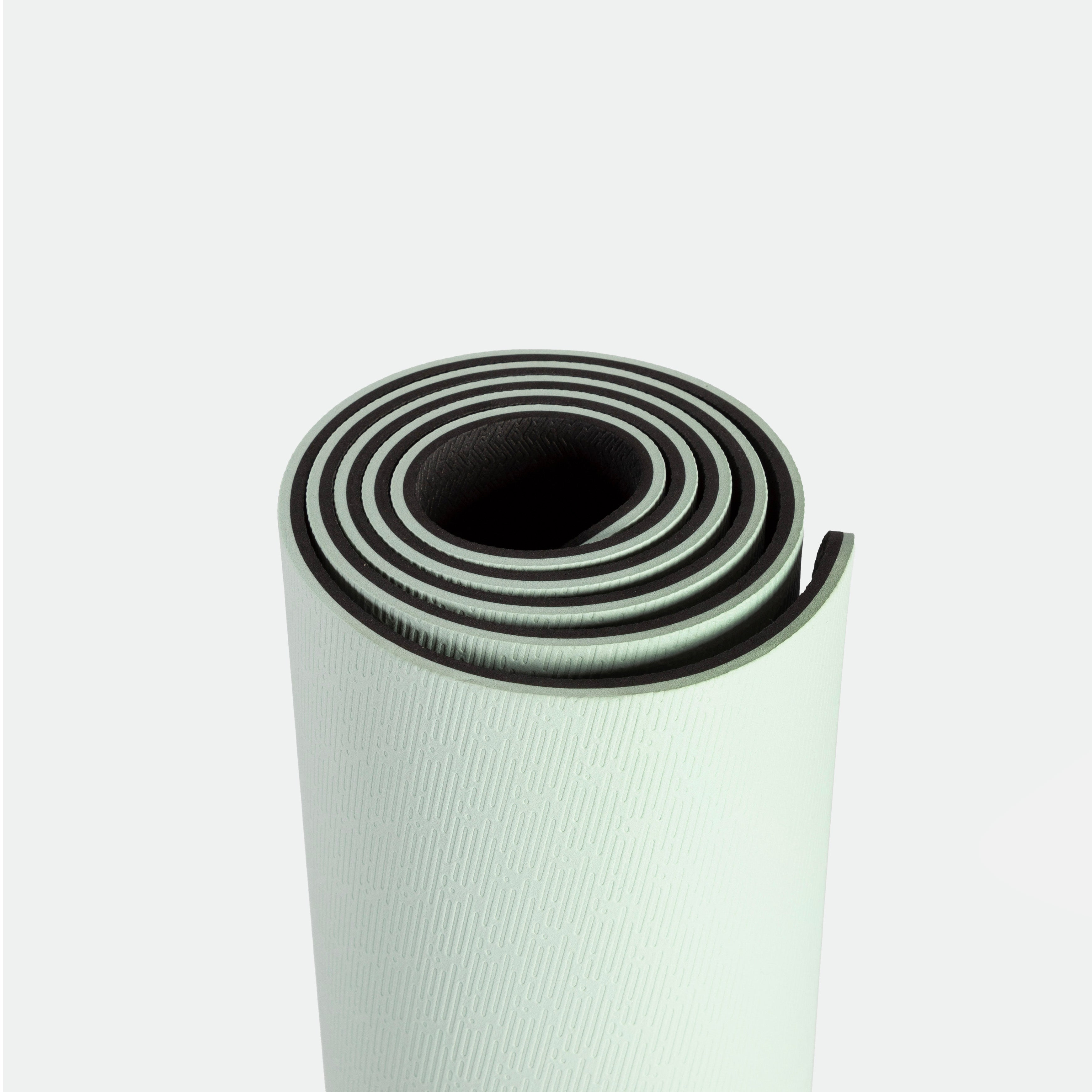 A rolled-up light green yoga mat with a textured surface and dark edges on a plain white background, conveying a sense of calm and readiness.