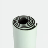 A rolled-up light green yoga mat with a textured surface and dark edges on a plain white background, conveying a sense of calm and readiness.