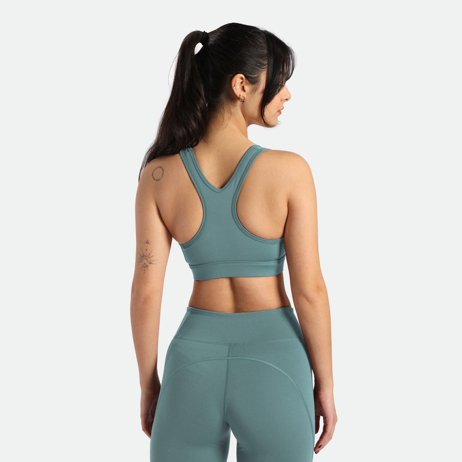 a woman wearing bra and legging ,She stands back ,with background light grey