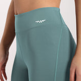 a fit woman wearing legging goblin blue   with logo white ,plus the background is light grey 